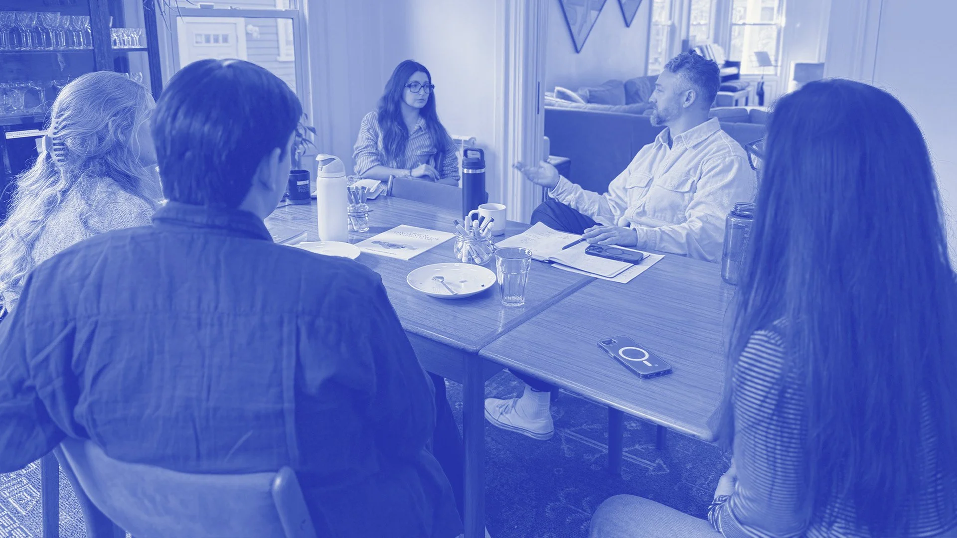 Team retreat around a table, intentional-blue duotone